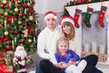 Christmas or New year celebration. Happy young family sitting near Christmas tree with xmas gifts. A fireplace with christmas stoc Royalty Free Stock Photo