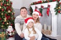 Christmas or New year celebration. Happy young family sitting near Christmas tree with xmas gifts. A fireplace with christmas stoc Royalty Free Stock Photo