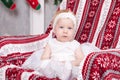 Christmas or New year celebration. Little cute girl in white festive dress sits in a chair with plaid with Christmas ornament. Hap Royalty Free Stock Photo
