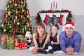 Christmas or New year celebration. Portrait of cheerful happy family of three people lying on the floor near Christmas tree with x Royalty Free Stock Photo