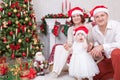 Christmas or New year celebration. Portrait of cheerful young family of three people near the Christmas tree with xmas gifts. A fi Royalty Free Stock Photo