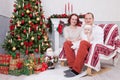 Christmas or New year celebration. Portrait of cheerful young family of three people near the Christmas tree with xmas gifts. A fi Royalty Free Stock Photo