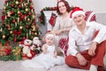 Christmas or New year celebration. Portrait of cheerful young family of three people near the Christmas tree with xmas gifts. A fi Royalty Free Stock Photo