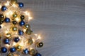 Christmas and New Year composition from blue and gold shiny and matte balls and christmas lights on light wood background