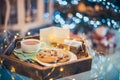 Christmas and New Year composition. Cocoa, cookies, little giftbox and postcard on the wooden tray with xmas tree background.