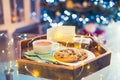 Christmas and New Year composition. Cocoa, cookies, little giftbox and postcard on the wooden tray with xmas tree background.