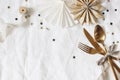 Christmas, New Year composition. Decorative table setting. Paper stars, golden cutlery and confetti stars on white linen Royalty Free Stock Photo