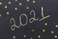 Chalk handwritten inscription 2021 on a black board. With golden stars.