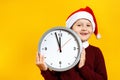 Christmas and new year concept. The child holds a clock on a yellow background. Royalty Free Stock Photo