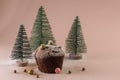 Christmas and New Year concept. Homemade chocolate muffin. Green Christmas trees in the snow on a pink gentle background. Copy