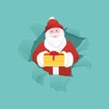 Santa Claus holding a gift box and peeking from ripped paper hole. Royalty Free Stock Photo