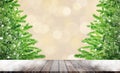 Wooden table and Green pine tree toy model with falling white snow in bokeh background.