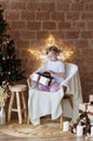 Christmas, New Year. Cute little girl in pajamas sitting on the chair Royalty Free Stock Photo