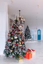 Christmas and New Year decorated interior room with red presents and New year tree in front of white wall. Royalty Free Stock Photo