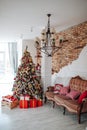 Christmas and New Year decorated interior room with red presents and New year tree and classic brown sofa in front of white wall. Royalty Free Stock Photo