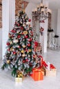 Christmas and New Year decorated interior room with red presents and New year tree in front of white wall. Royalty Free Stock Photo