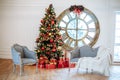 Christmas and New Year decorated white interior room with presents and New year tree with red decor ball. Grey sofa and