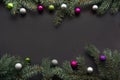 Christmas or New Year decoration background: fir-tree branches, colorful glass balls on black background with copy space. Top view Royalty Free Stock Photo