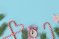 Christmas or New Year decoration background: sweet Christmas canes, pink clock and Christmas tree branches on a blue Royalty Free Stock Photo