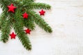 Christmas and New Year design with a branch of green spruce and red stars. White wooden background. Royalty Free Stock Photo