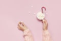 Christmas New Year drink, white mug with marshmallows in female hands in knitted sweater and Candy Cane on pink background top