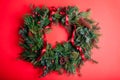 Christmas and New Year wreath made of fir, pine evergreen branches, rose hips, cones decorated with red ribbon bow. Royalty Free Stock Photo