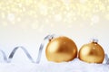 Christmas and New Year greeting card. Holiday ornament, winter decoration. Gold christmas balls with silver ribbon in snow over Royalty Free Stock Photo