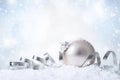 Christmas and New Year greeting card. Holiday ornament, winter decoration. Silver christmas ball with ribbon over snow background Royalty Free Stock Photo