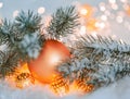 Christmas and New Year Holiday greeting card. Beautiful orange ball, pine branches and a garland in the snow. Royalty Free Stock Photo