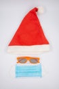 Christmas and New Year holidays in coronavirus pandemic. Red Santa hat, goggles and a protective medical face mask to protect Royalty Free Stock Photo