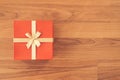 Christmas and New Year holidays gift box wrapped with red paper and yellow ribbon bow on wood table - top view on wooden table top Royalty Free Stock Photo