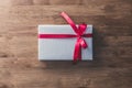Gift box wrapped with silver gray paper and red ribbon bow on wood table Royalty Free Stock Photo