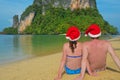 Christmas and New Year holidays on tropical beach, romantic couple in santa hats sitting near sea Royalty Free Stock Photo