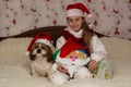 Christmas or New Year online congratulations. Smiling girl in santa hat with dog in santa hat Royalty Free Stock Photo