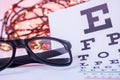 Christmas and New Year in ophthalmology optometry. Eyeglasses and ophthalmological table for visual acuity test in foreground with Royalty Free Stock Photo