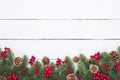 Christmas and New Year`s composition. Top view of spruce branches, pine cones, red berries and bell on white wooden table Royalty Free Stock Photo