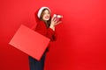 Christmas and New Year shopping. Pretty young woman in Santa's hat with packages and gifts on a red background Royalty Free Stock Photo