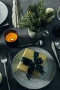 Christmas or New Year Table Setting. Craft blue plate with cutlery and gift box, fir tree branches Royalty Free Stock Photo