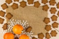 Christmas or New Year tangerines and gingerbread cookies with snowflakes framed on brown sack background texture.