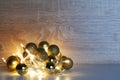 Christmas and New Year template from gold shiny, sparkling, matte christmas balls illuminated by a led garland on light oak wood Royalty Free Stock Photo