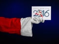 Christmas and New Year 2016 theme: Santa Claus hand holding a white gift card on a dark blue background in studio isolated Royalty Free Stock Photo