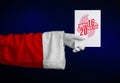 Christmas and New Year 2016 theme: Santa Claus hand holding a white gift card on a dark blue background in studio isolated Royalty Free Stock Photo