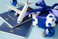 Christmas or New Year travel concept. Toy airplane with passports and gift box on blue background