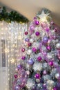 Christmas or New Year tree decorated with purple baubles, shiny star on top and garland lights with two white lanterns Royalty Free Stock Photo