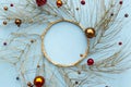 Christmas or new year winter composition. Round frame made of golden tree branches and red decorative Christmas ornaments on blue Royalty Free Stock Photo