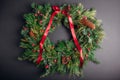 Christmas and New Year wreath made of fir, pine evergreen branches, rose hips, cones decorated with red ribbon bow. Royalty Free Stock Photo