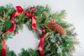 Christmas and New Year wreath made of fir, pine evergreen branches, rose hips, cones decorated with red ribbon bow Royalty Free Stock Photo