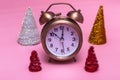 Christmas or New Years minimal concept. Alarm clock and multicolored Christmas trees on a pink background Royalty Free Stock Photo