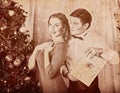 Christmas nostalgy couple on party near Xmas tree take gift box.