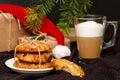 Christmas oat cookies, mug of coffee or cappuccino, gift boxes in kraft paper, hat of Santa Claus on brown background